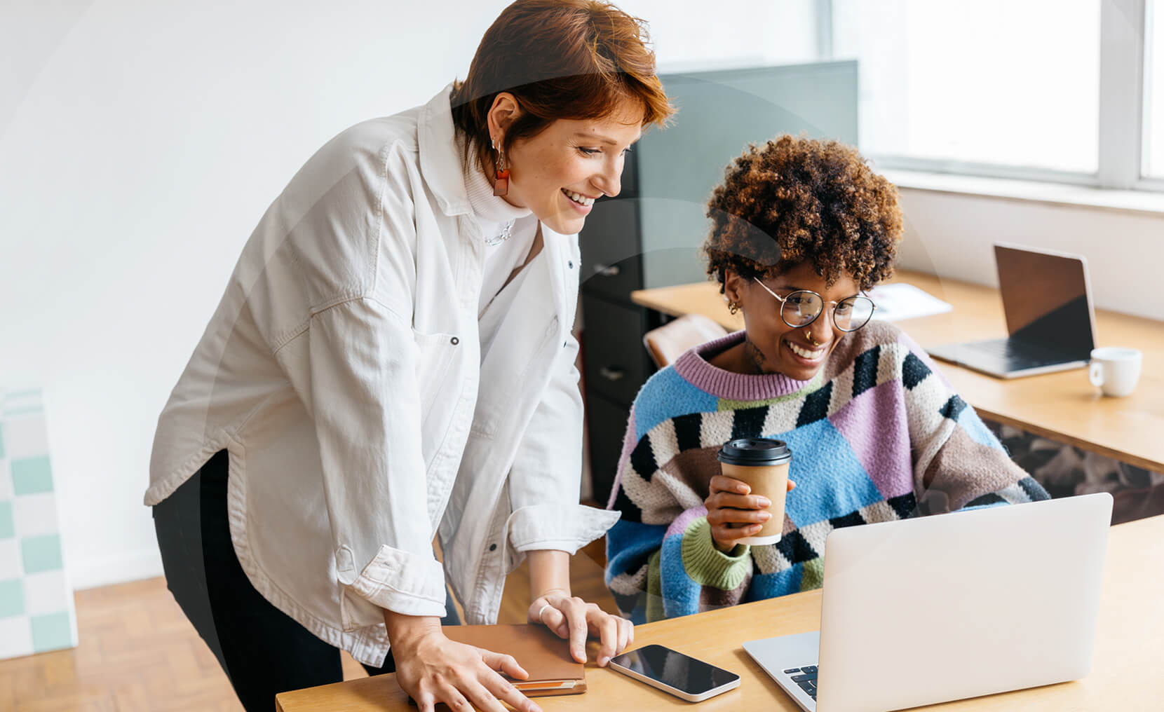 Two women smiling and looking at a laptop while they explore content trends for SEO success.