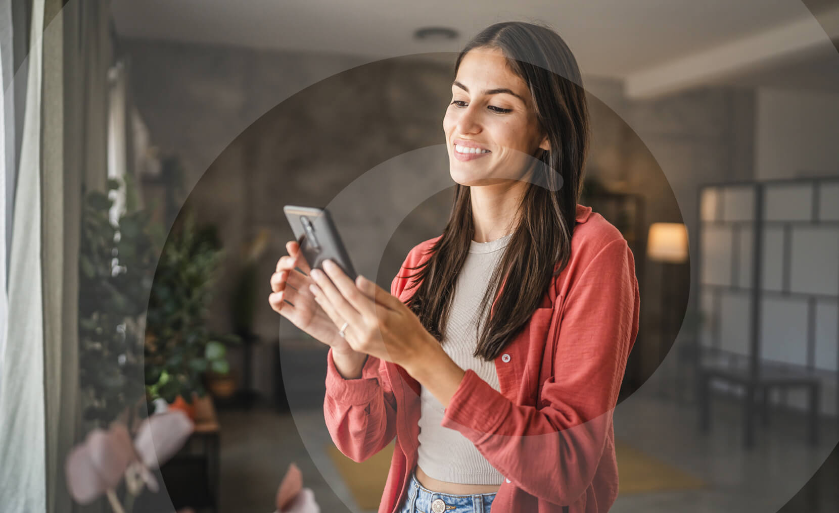 Woman smiling while using a smartphone indoors